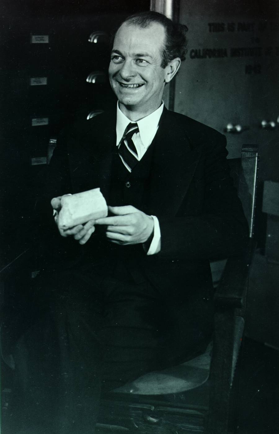 Linus Pauling in a Caltech laboratory, holding a rock specimen.