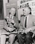 Linus Pauling, holding a model of the alpha-helix, seated next to George Beadle.
