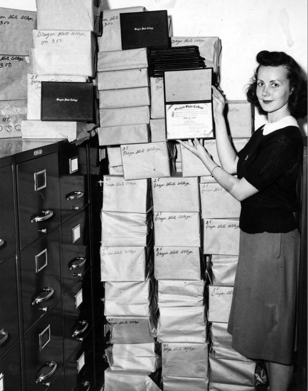 Beverly Everett, Registrar's Office clerk, displaying the diplomas in her office, 1948.