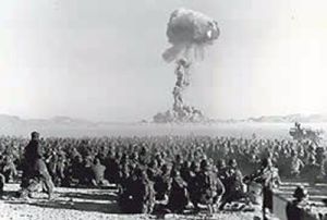 View of mostly seated spectators and cloud during bomb test