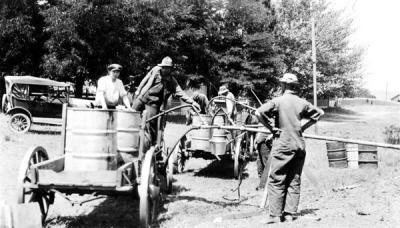 Men filling up oil drums, ca. 1919.