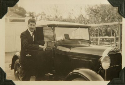 Black and white photograph of Roger Hayward posing with his automobile.