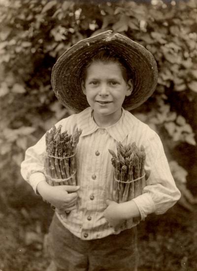An unidentified child holding asparagus, ca 1920s.