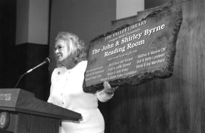Joan Austin holding a sign for the Valley Library's John and Shirley Byrne Reading Room, a gift given to Byrne, OSU President, upon his retirement. March 1996.