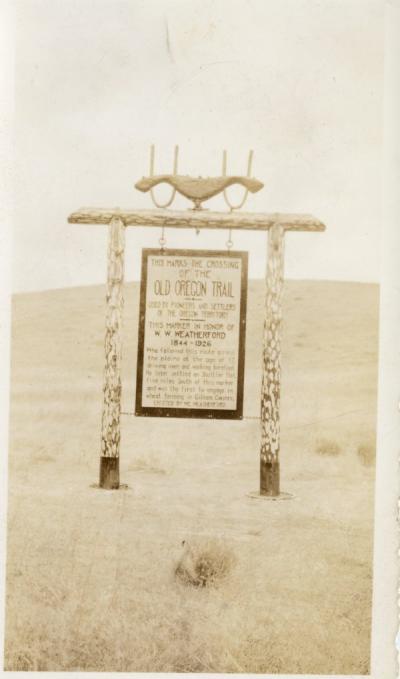 Old Oregon trail marker, ca 1920s. Sign reads: "This marks the crossing of the Old Oregon Trail used by pioneers and settlers of the Oregon Territory. This marker in honor of W. W. Weatherford, 1844-1926. Who followed this route across the plains at the age of 17, driving oxen and walking barefoot. He later settled on Shuttler Flat, five miles south of this marker, and was the first to engage in wheat farming in Gilliam County. Erected by M. Weatherford."