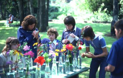 Several 4-H youth gathered around a table participating in the flower identification contest, 1975.