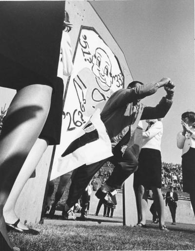 Dee Andros (the Great Pumpkin) leading the football team onto the field before the Homecoming game against Idaho, 1966. Andros was the Oregon State Head Coach for football from 1965-1975, and Athletic Director from 1975-1985. In 1967 Andros lead the OSU "Giant Killers" team to two victories and one tie against the top three teams in the country: USC, Purdue and UCLA.
