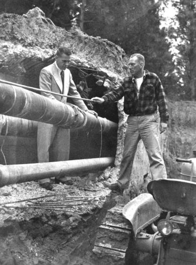 Otto Meyer of the OSC physical plant (left) and V.A. Stanford of Donald Drake Construction in Portland (right) manipulating a pipe being installed in a new campus heating tunnel, June 1951.